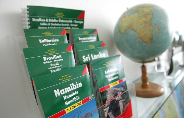 Ein Regal mit Reiseführern für verschiedene Länder und einem Globus im Hintergrund.
