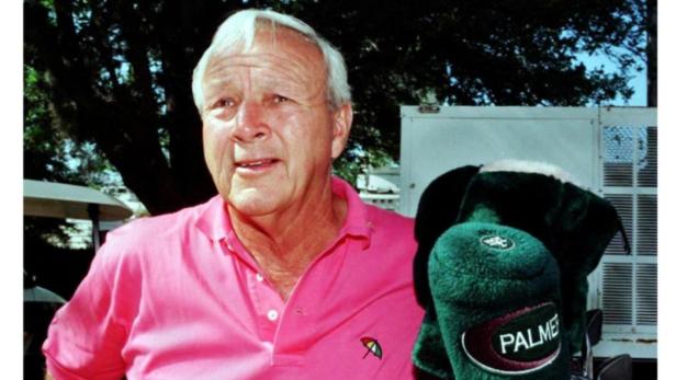 Arnold Palmer mit einem rosafarbenen Poloshirt und einem Golfschlägerüberzug mit seinem Namen.
