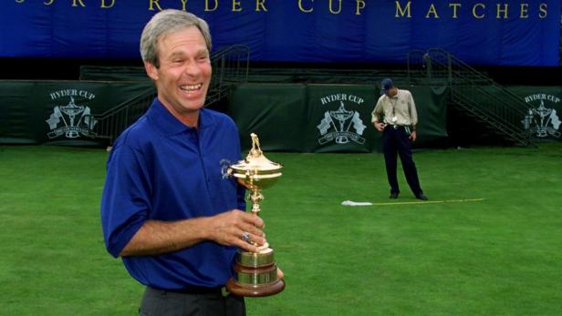 Ein Mann hält den Ryder Cup in seinen Händen und lächelt.