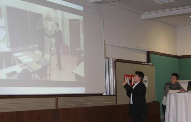 Ein junger Mann hält eine Präsentation vor einem Publikum.