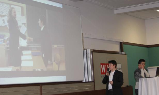 Ein junger Mann hält ein Mikrofon während einer Präsentation vor Publikum.