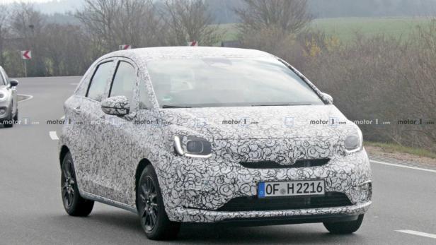 Ein mit Tarnmuster beklebter Honda Jazz fährt auf einer Landstraße.