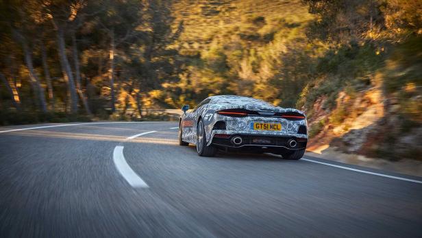 Ein getarntes McLaren-Auto fährt auf einer kurvenreichen Straße entlang.