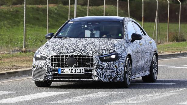 Ein Prototyp eines Mercedes-Benz CLA mit Tarnmuster auf einer Straße.