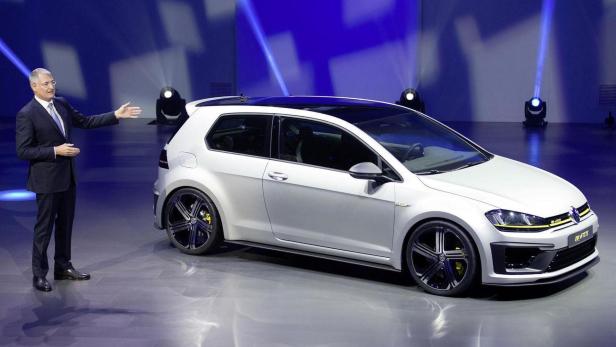 Ein Mann präsentiert einen weißen VW Golf R400 auf einer Bühne.