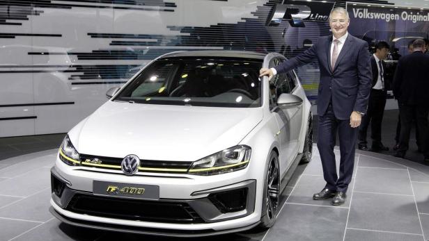 Ein Mann im Anzug posiert neben einem weißen VW Golf R400.