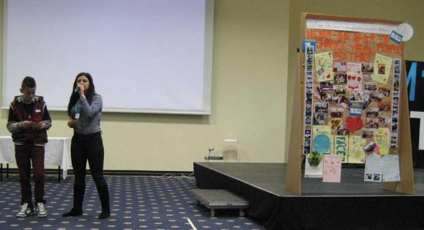 Eine junge Frau spricht auf einer Bühne, während ein Junge daneben steht.