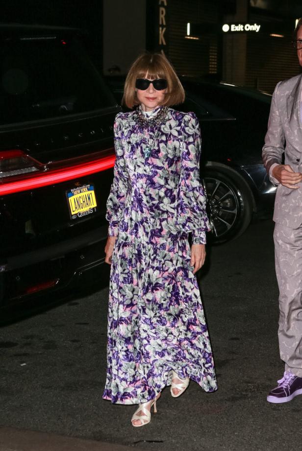 Anna Wintour Anna Wintour in einem lilafarbenen Blumenkleid und Sonnenbrille vor einem schwarzen Auto.
