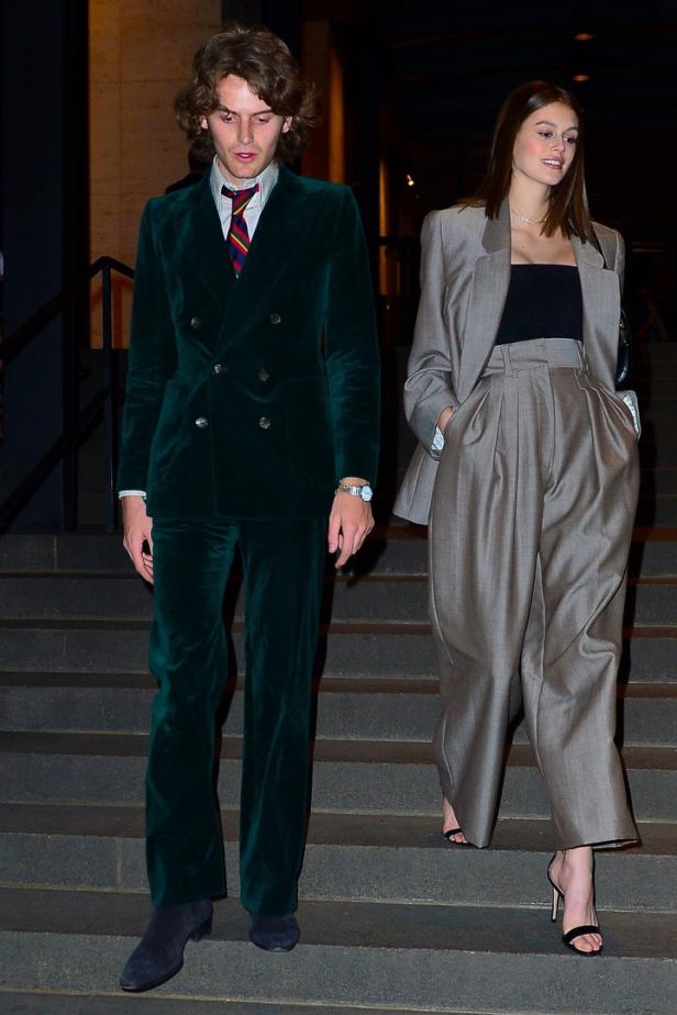 Kaia Gerber und Wellington Grant Ein Mann im grünen Samtanzug und eine Frau im grauen Hosenanzug gehen eine Treppe hinunter.