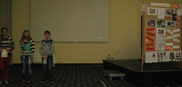 Drei Jugendliche stehen auf einer Bühne vor einem Publikum.