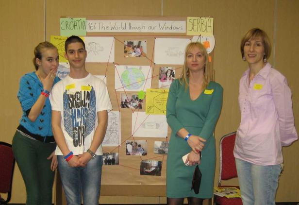 Vier Personen stehen vor einer Pinnwand mit dem Titel „Croatia Serbia The World through our Windows“.