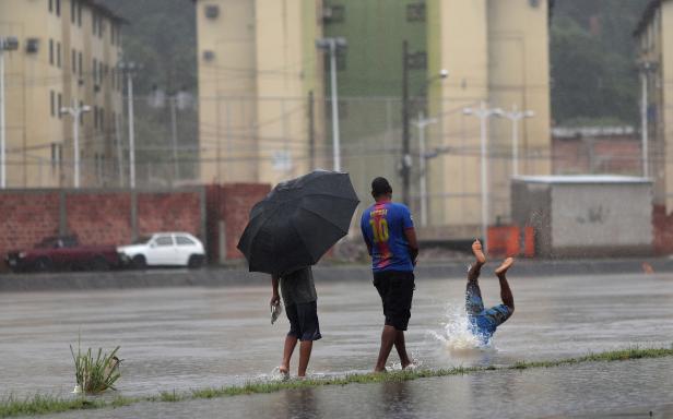 A man dives into a flooded channel during heavy rains in the Fazenda Botafogo neighbourhood in Rio de Janeiro