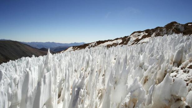 Ein Feld aus Penitentes im Hochgebirge unter blauem Himmel.