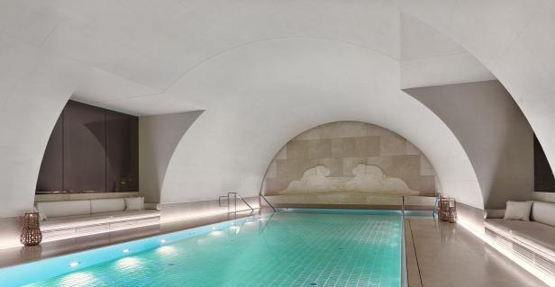 Ein Schwimmbad mit hellblauem Wasser in einem eleganten, gewölbten Raum.