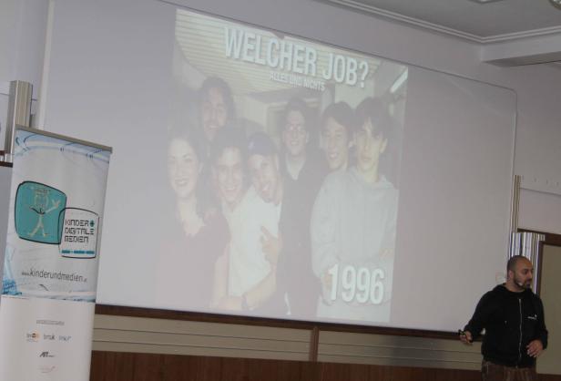 Ein Mann präsentiert eine Folie mit dem Titel „Welcher Job? Alles und Nichts“ und einem Foto von Jugendlichen aus dem Jahr 1996.