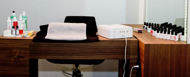 Ein Nagelpflegeset mit Lacken, Handtüchern und einer UV-Lampe auf einem Holztisch.