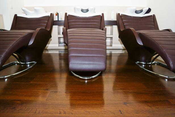Drei braune Friseurstühle mit weißen Waschbecken in einem Friseursalon.