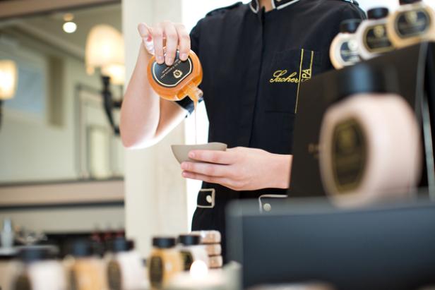 Eine Person gießt eine Flüssigkeit aus einer Flasche in eine Schale im Sacher Spa.