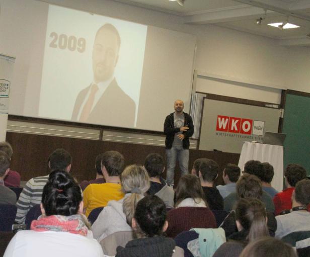 Ein Mann hält einen Vortrag vor Publikum, im Hintergrund eine Leinwand mit einem Porträt und der Zahl 2009.