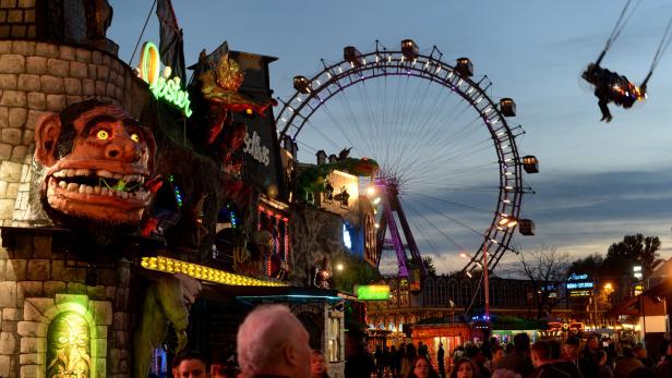 Das Wiener Riesenrad und ein Geisterschloss auf dem Wiener Prater im Abendlicht.