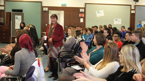 Eine Frau hält einen Vortrag vor einem applaudierenden Publikum.