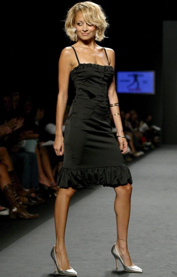 Nicole Richie läuft in einem schwarzen Kleid und silbernen Schuhen über den Laufsteg.