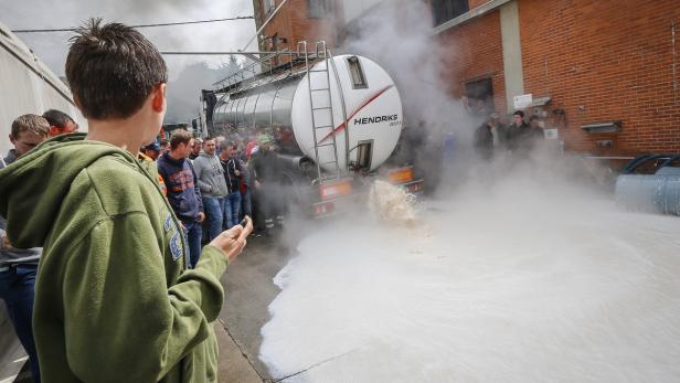 Ein Tankwagen der Firma Hendriks leert eine große Menge Milch auf eine Straße, umringt von Zuschauern.