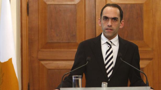 Ein Mann in Anzug und Krawatte steht vor einem Mikrofonständer.