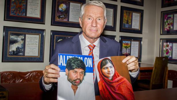 Ein Mann im Anzug hält Fotos von Malala Yousafzai und Kailash Satyarthi.