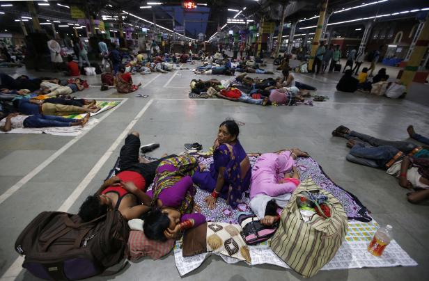 Stranded passengers rest inside a railway station after trains between Kolkata and Odisha were cancelled ahead of Cyclone Fani, in Kolkata