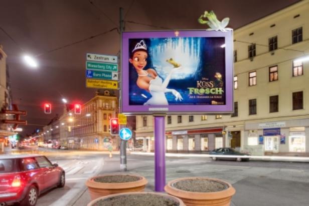 Eine Werbetafel in einer Stadt zeigt den Film „Küss den Frosch“.