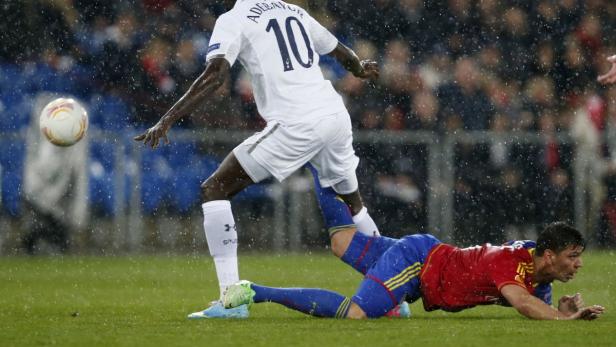 Bei Regen spielt Adebayor Fußball, während ein anderer Spieler am Boden liegt.