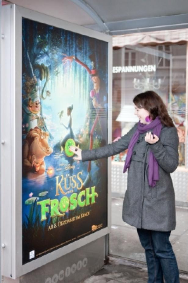 Eine Frau betrachtet ein Plakat für den Disney-Film „Küss den Frosch“.