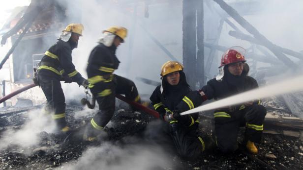 Feuerwehrleute bekämpfen einen Brand in einem zerstörten Gebäude mit Wasser.