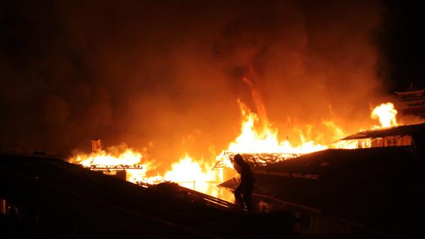 Ein Gebäude steht in Flammen, Rauch steigt auf.