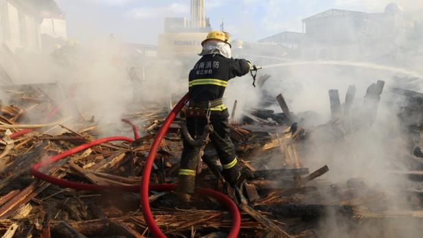 Ein Feuerwehrmann bekämpft ein Feuer auf einem Trümmerhaufen mit einem Wasserstrahl.