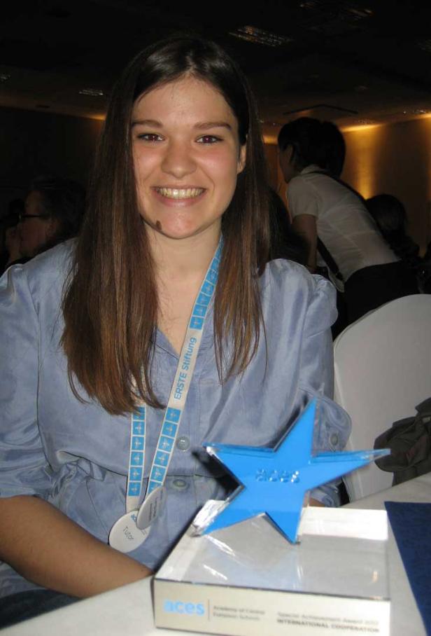 Eine lächelnde junge Frau mit einem blauen Stern-Award der „Academy of Central European Schools“.