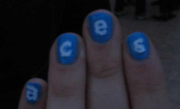 Nahaufnahme einer Hand mit blau lackierten Fingernägeln, die die Buchstaben „aces“ zeigen.