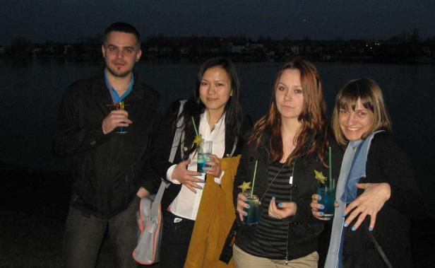 Eine Gruppe von vier Personen posiert mit blauen Cocktails vor einem dunklen Hintergrund.