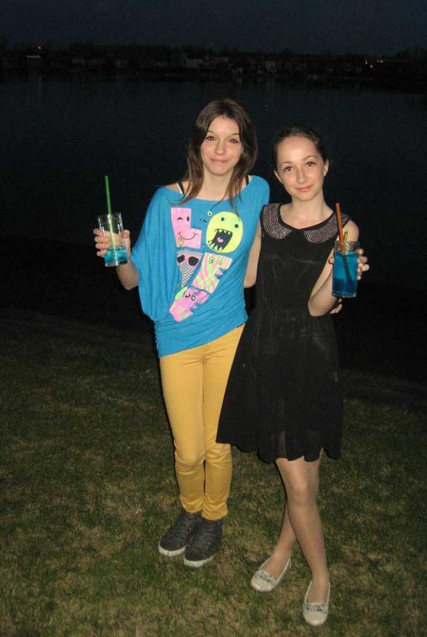 Zwei junge Frauen posieren mit blauen Getränken im Freien.