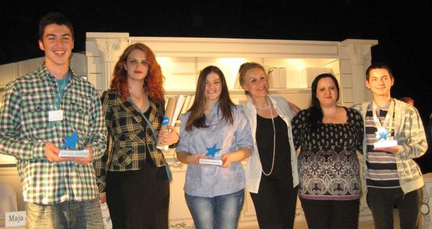 Eine Gruppe junger Leute posiert mit blauen Stern-Trophäen für ein Foto.