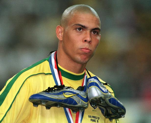 Ronaldo trägt ein Trikot der brasilianischen Nationalmannschaft und Fußballschuhe um den Hals.