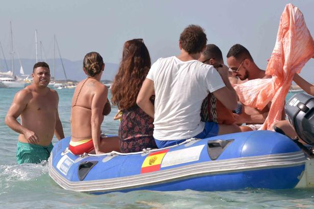 Ronaldo steht im Wasser neben einem blauen Schlauchboot mit mehreren Personen.