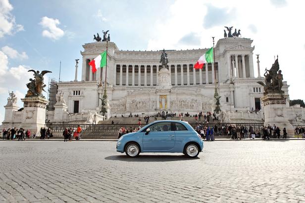 Ein blauer Fiat 500 vor dem Nationaldenkmal für Viktor Emanuel II. in Rom.