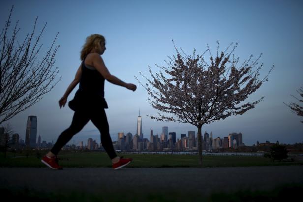 Eine Frau geht mit der Skyline von New York im Hintergrund spazieren.