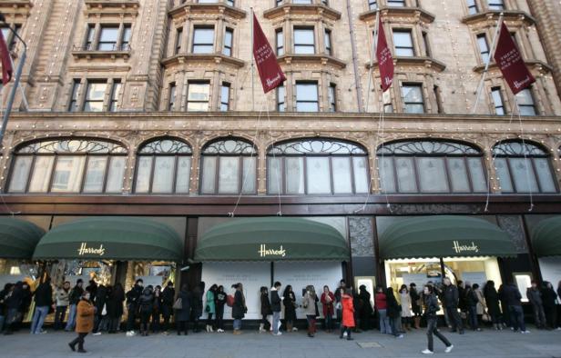Menschen stehen vor dem Harrods-Kaufhaus in London Schlange.