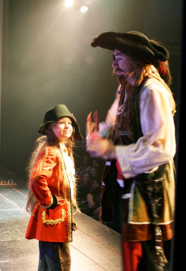 Ein Mädchen und ein Mann, beide als Piraten verkleidet, stehen auf einer Bühne.