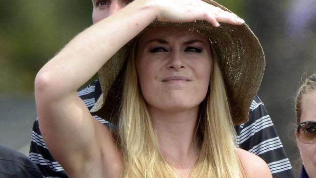 Eine blonde Frau mit Hut schirmt ihre Augen vor der Sonne ab.