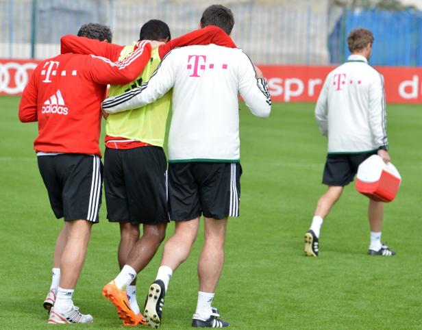 Alaba musste vom Platz begleitet werden. Drei Fußballspieler umarmen sich auf dem Trainingsplatz, ein weiterer geht mit einer Kühlbox weg.