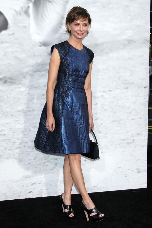 Winona Ryder in einem blauen Kleid und schwarzen Schuhen auf dem roten Teppich.